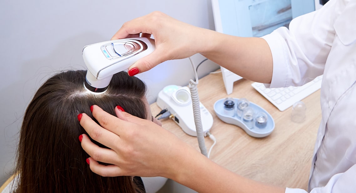 Dermatologist performing a trichoscopy scalp examination on a patient at Clear Skin Clinic, checking hair and follicle density before treatment planning